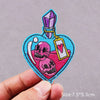 Embroidered horror movie patch featuring a skull and crossbones design with a purple gemstone charm