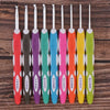 A set of ten ergonomic felt crochet hooks in various colors and sizes displayed on a wooden surface.