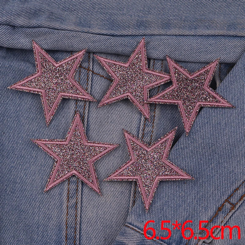 Five glitter iron-on embroidered love heart star patches on a denim fabric background
