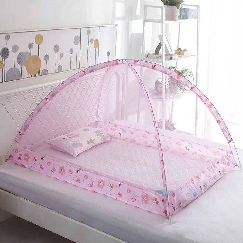 Pink foldable mosquito net covering an infant crib with decorative floral patterns.