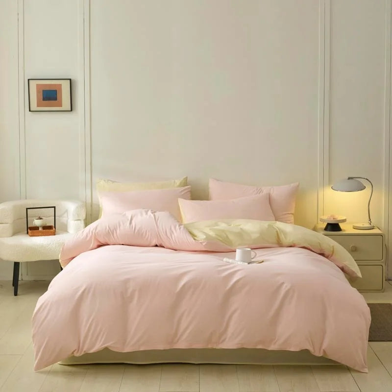 A pink duvet cover set with pillows and a matching pink bedspread on a light wood floor.