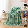 A teal soft flannel throw blanket draped over a chair in a bright room.