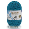 A skein of teal blue milk cotton yarn with a label featuring a dog illustration and stitching information.