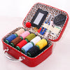 A red portable sewing kit box with an orange leopard print lid, containing various colored threads and a pair of scissors.