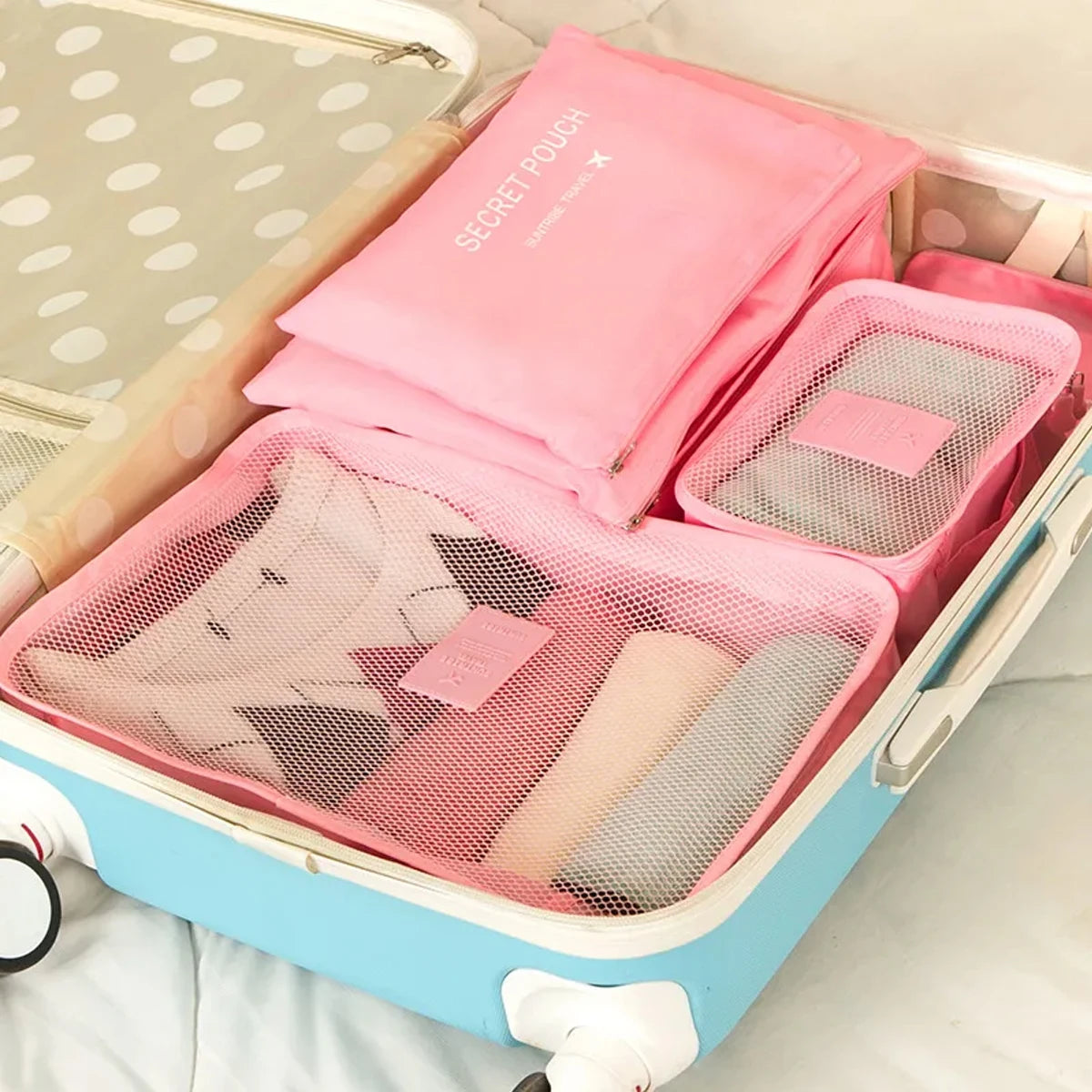 A pink travel organizer storage set with a lid and multiple mesh compartments for organizing toiletries or small items.