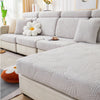 A light gray leaf jacquard stretch sofa cover displayed on a modern sectional sofa with white pillows.