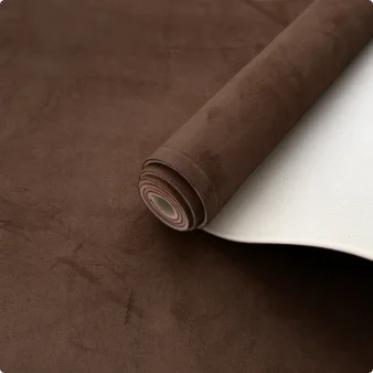 Roll of brown suede auto headliner fabric with foam backing resting on a dark brown surface.