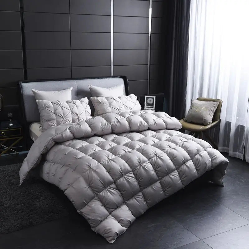 A quilted gray luxury goose down duvet blanket displayed on a bed in a modern bedroom.