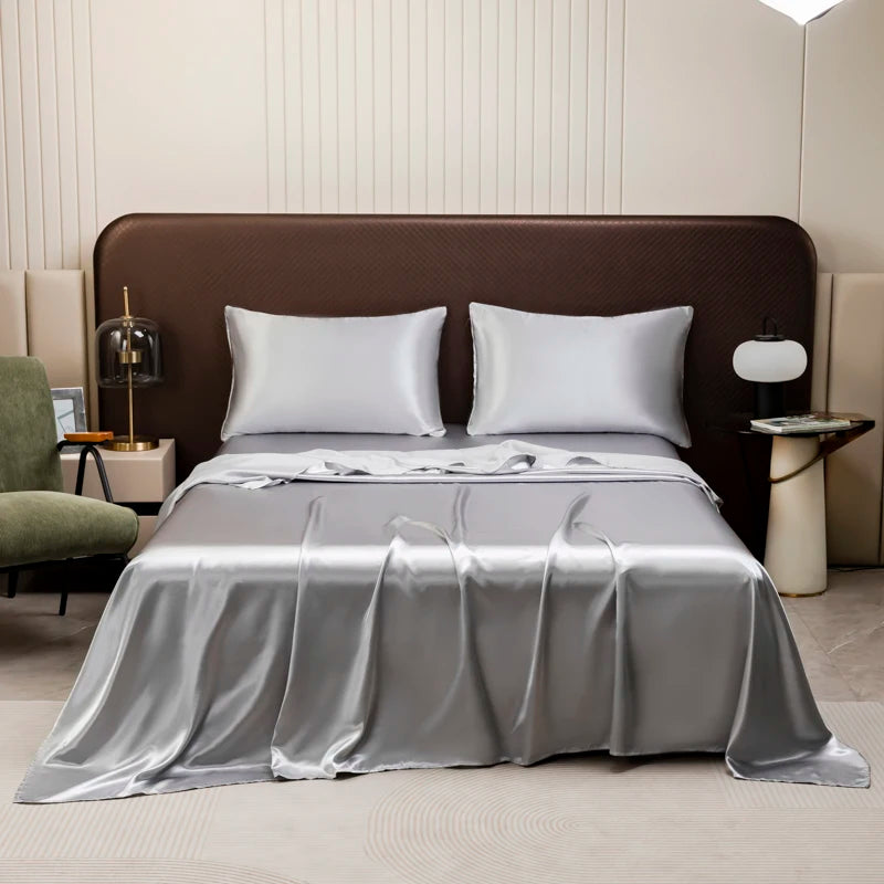 A luxurious bedroom featuring a bed dressed with a satin flat sheet set in silver and white colors.