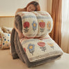 A woman is relaxing under a super thick lambswool winter blanket with floral embroidery.