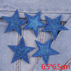 Five blue glitter star patches are displayed on a denim fabric background.