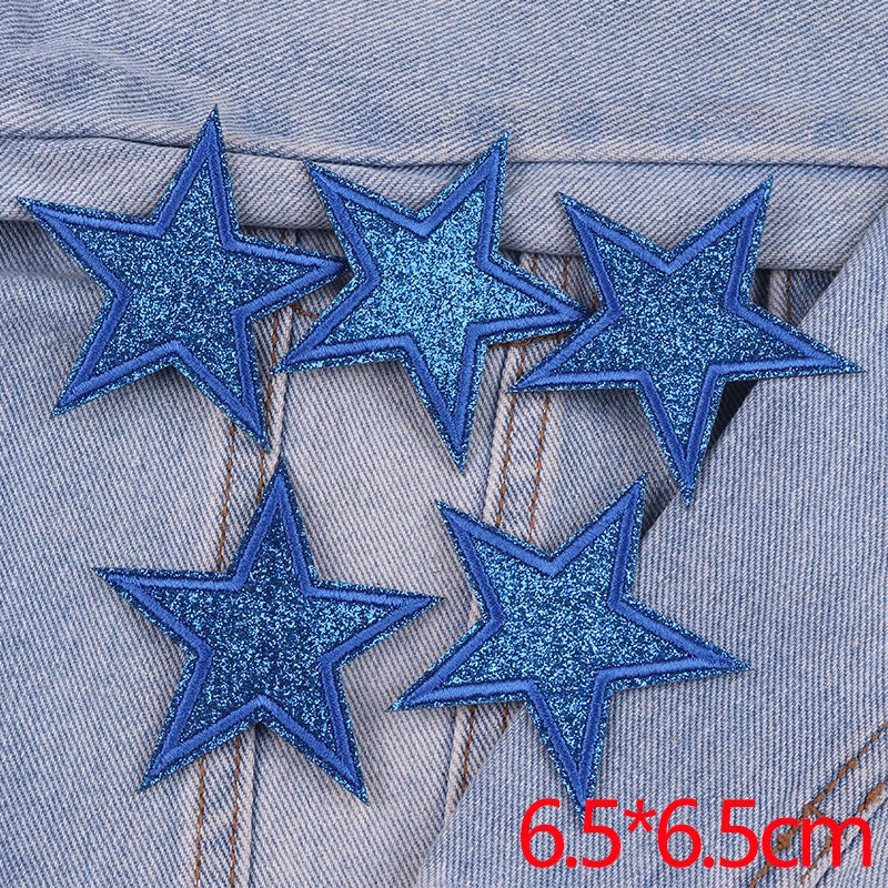 Five blue glitter star patches are displayed on a denim fabric background.