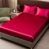 A luxurious bedroom featuring a bed dressed in vibrant pink satin bedding and pillows.