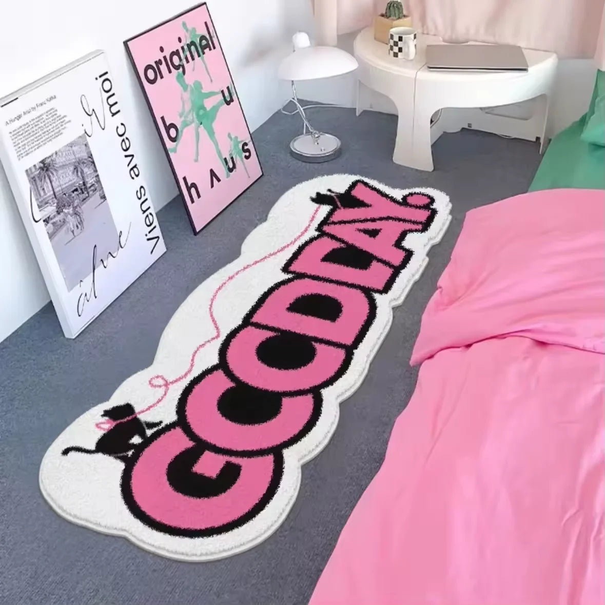 A pink and black cartoon decorative floor mat with the text GOODDAY is displayed on a gray floor.