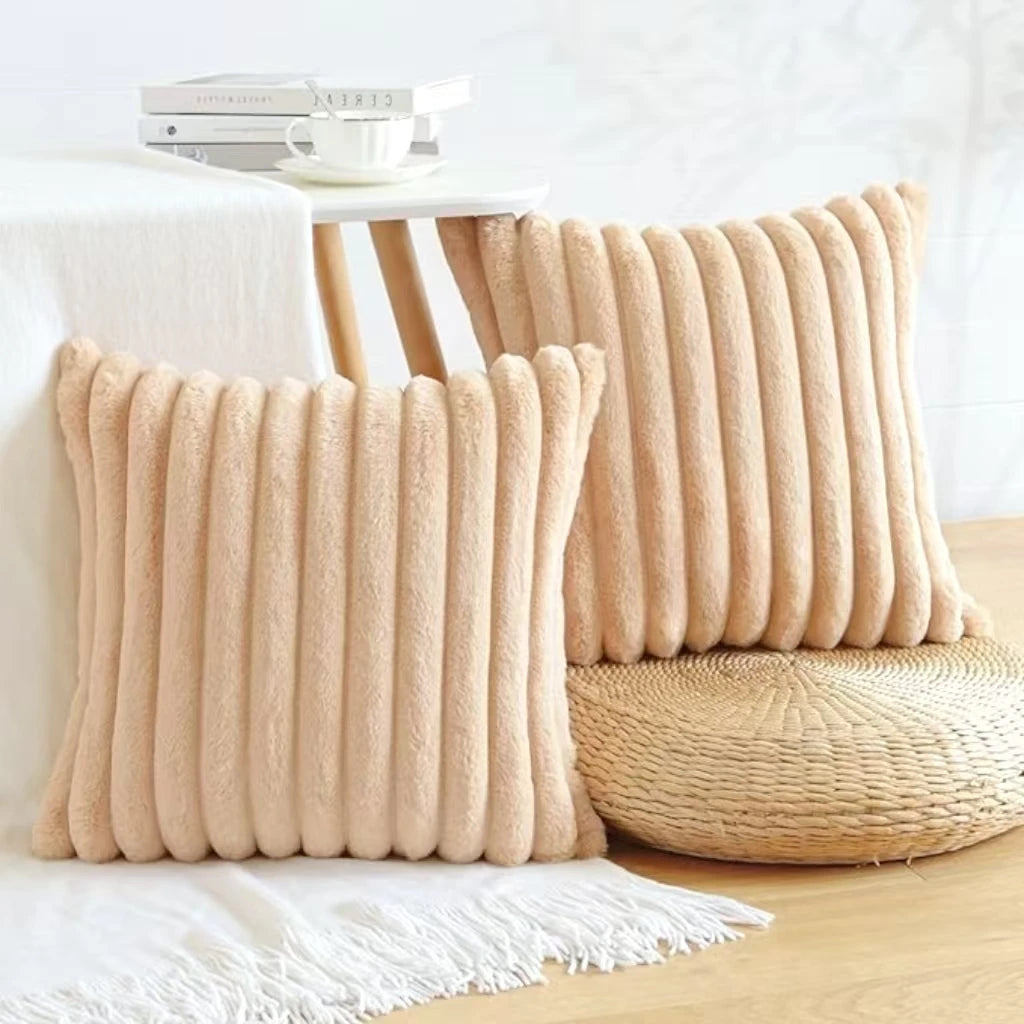 Two beige plush striped decorative pillowcases resting on a white surface.