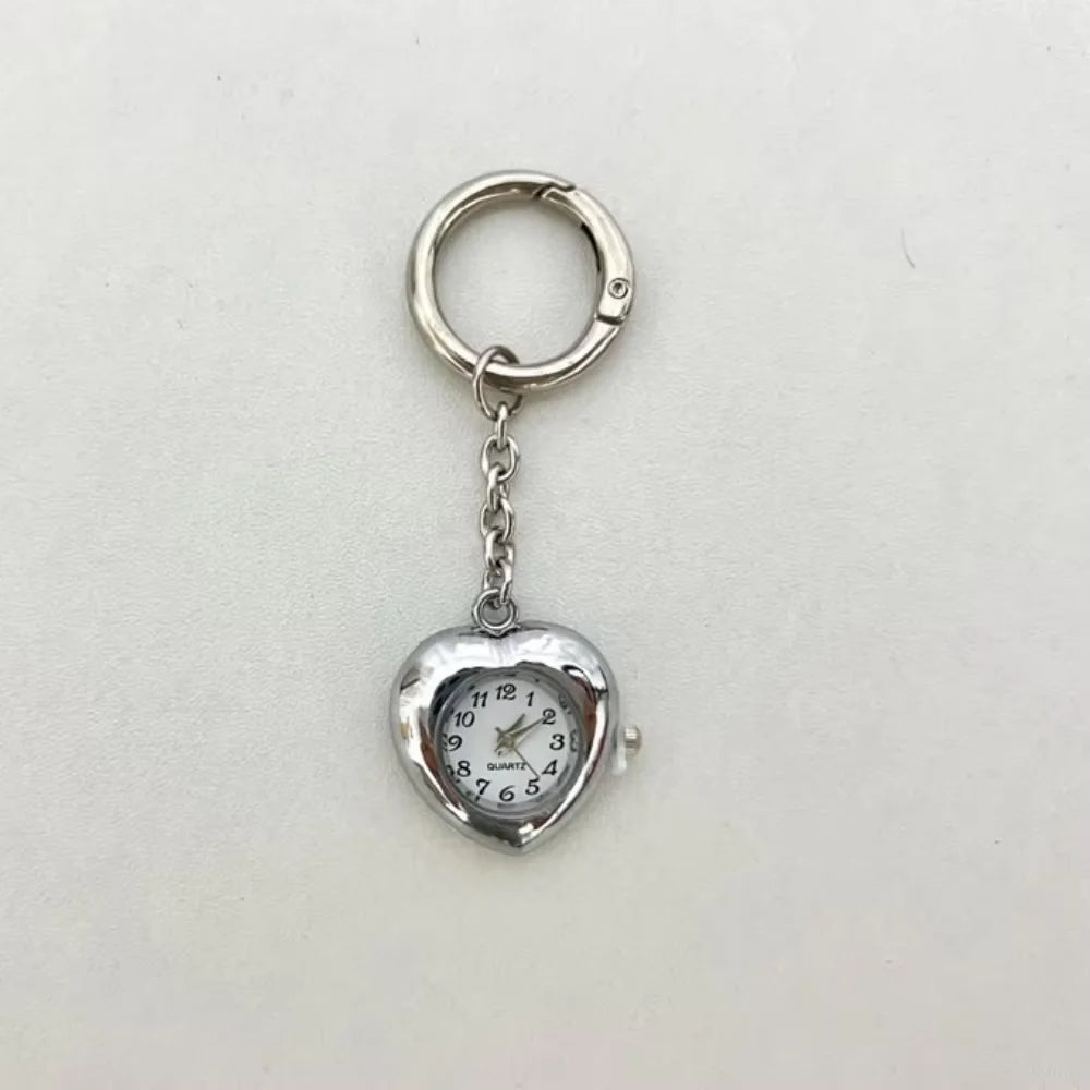 Silver heart-shaped pocket watch keychain with a round face and hands
