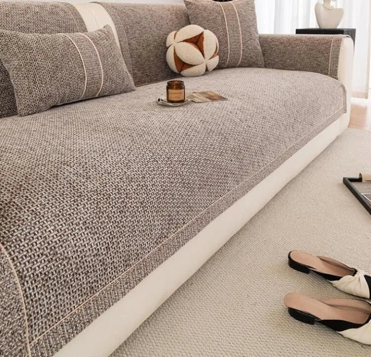 A textured gray sofa cushion cover with a white trim, featuring decorative pillows and a small candle.