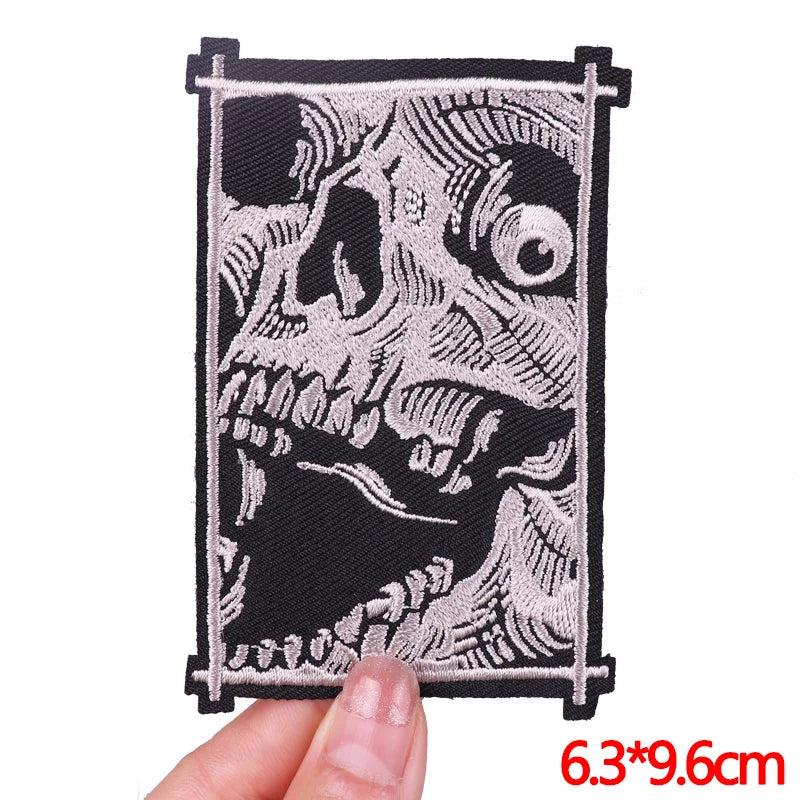 A black embroidery patch featuring a detailed skull design in light gray thread.