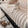 A fluffy gray cat is relaxing on a thick, ribbed, cream-colored plush sofa seat cushion.