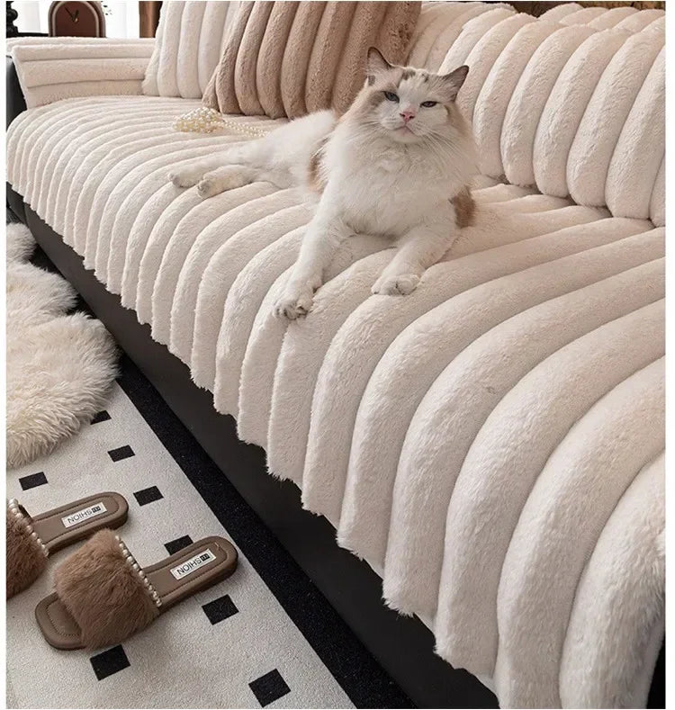 A fluffy gray cat is relaxing on a thick, ribbed, cream-colored plush sofa seat cushion.