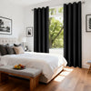 Blackout thermal window drapes framing a bright window in a modern bedroom setting.