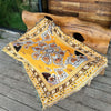 A yellow and white bohemian geometric throw blanket draped over a large wooden log.