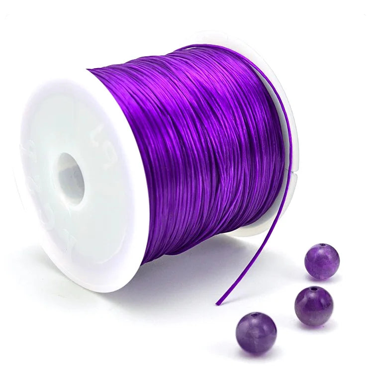 Purple elastic beading cord wound on a white spool with loose strands extending from it.