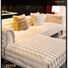A cream colored plush velvet sofa cover with a quilted texture and fluffy pillows displayed in a modern interior setting.
