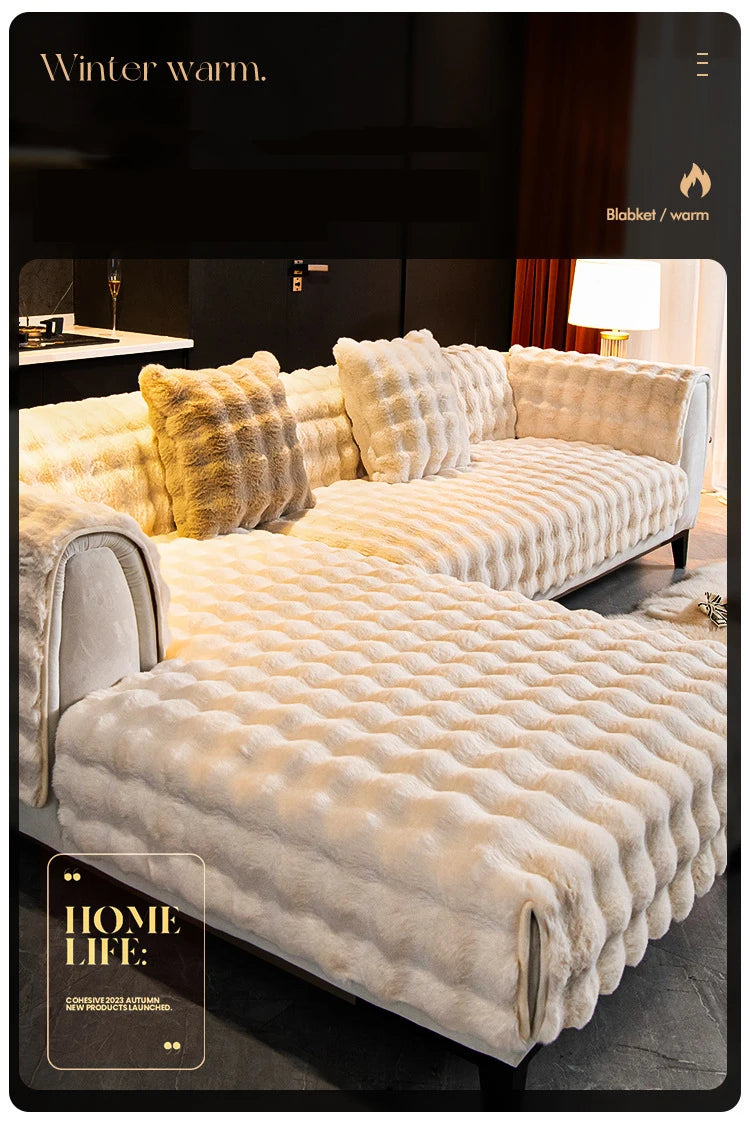A cream colored plush velvet sofa cover with a quilted texture and fluffy pillows displayed in a modern interior setting.
