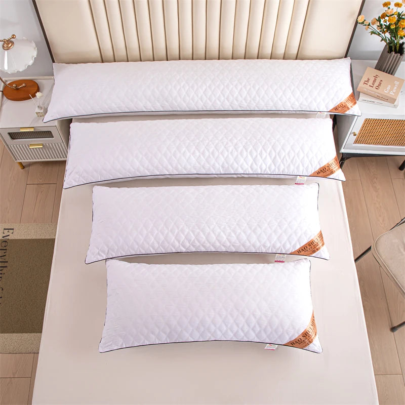 A set of four white rectangular sleeping pillows with gold accents displayed on a light-colored surface.
