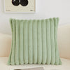 A light sage green faux fur stripe decorative throw pillow cover displayed on a white sofa.