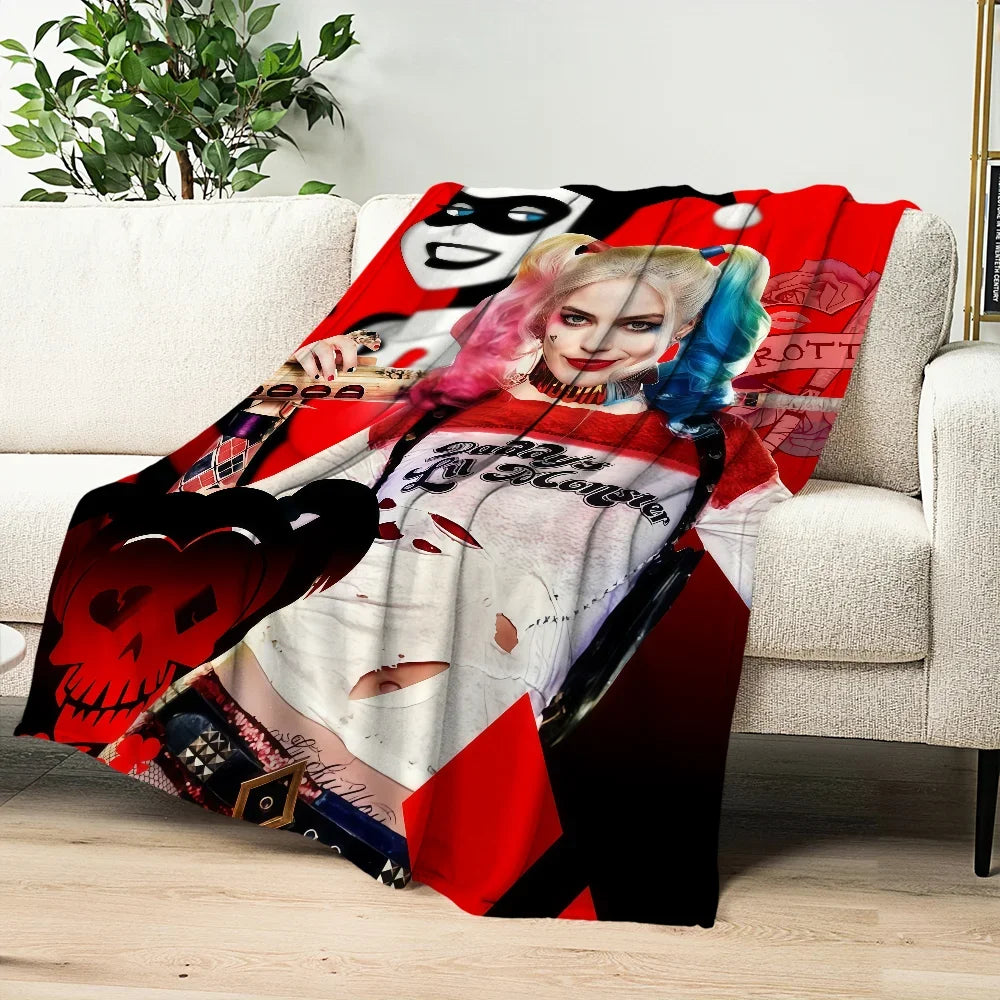 A red and black graphic blanket featuring a stylized woman's face and pink hair on a white sofa.
