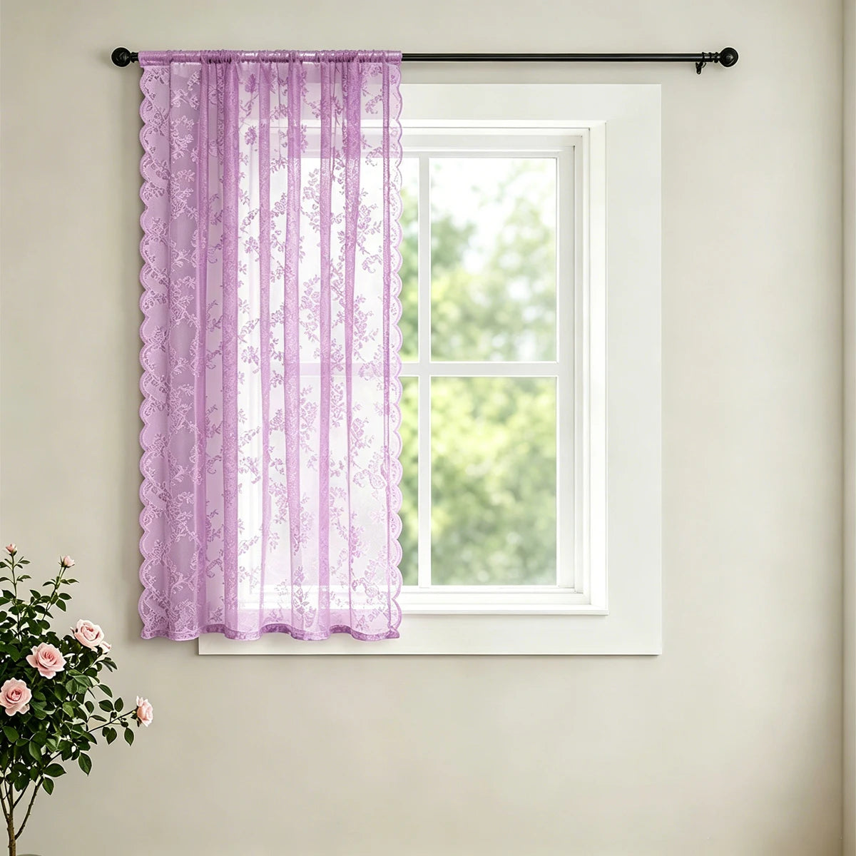 A sheer lavender lace curtain with a delicate floral pattern hanging in a white window frame.