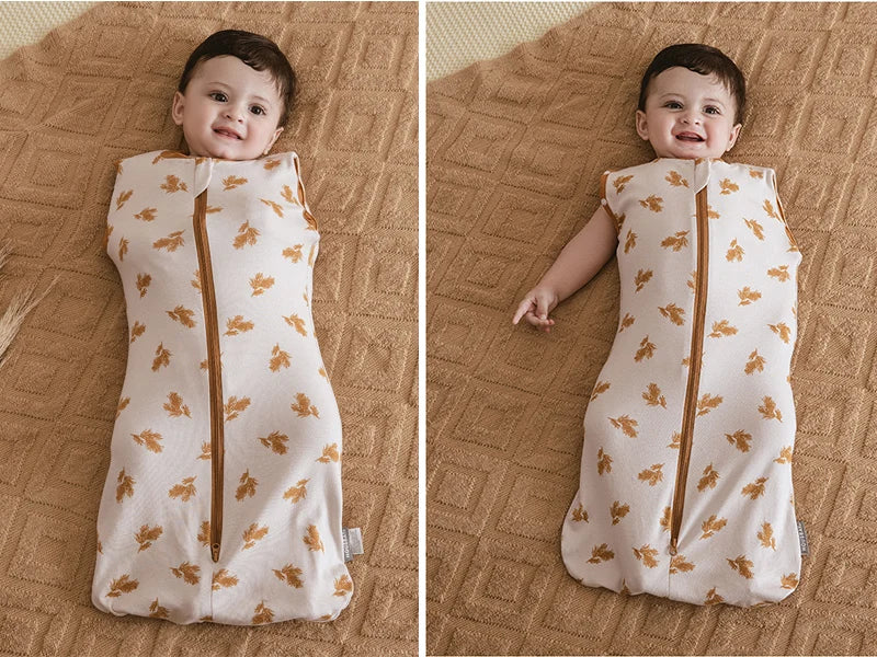 A baby wearing a light beige cotton sleeping bag or swaddle with a subtle floral pattern.