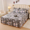 A luxury floral bed skirt in gray and purple flowers covers a bed with a light upholstered headboard.
