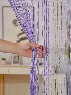 A hand is holding and adjusting purple decorative door string curtains for windows.