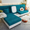 A teal jacquard elastic sofa slipcover with white accents and decorative pillows in a modern living room setting.