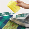 A hand holds a yellow transparent resin quilting ruler set on a green grid surface.