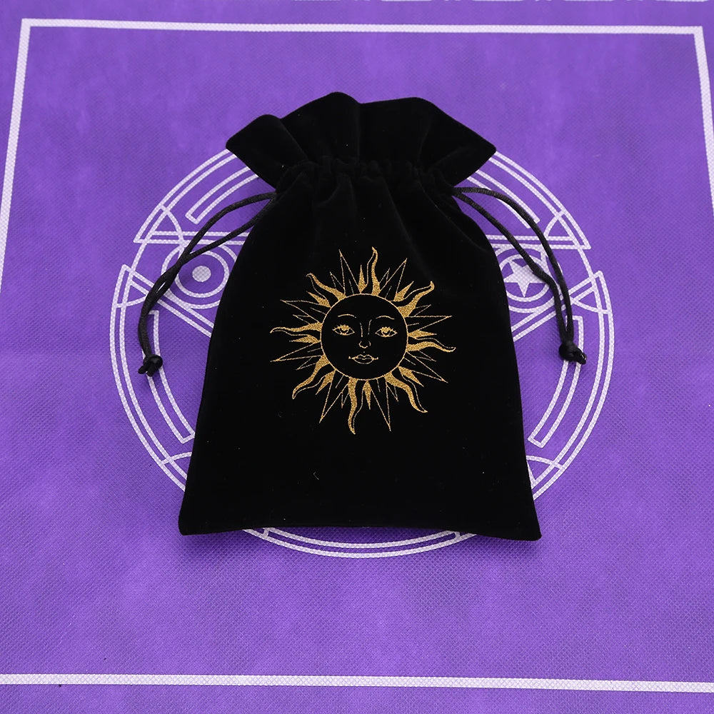 A black velvet pouch with a gold sun symbol is placed on a purple mat.