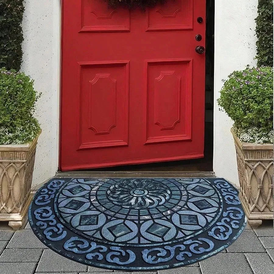 A vintage stone doormat with an intricate blue and white pattern lies on a gray stone step in front of a red door.