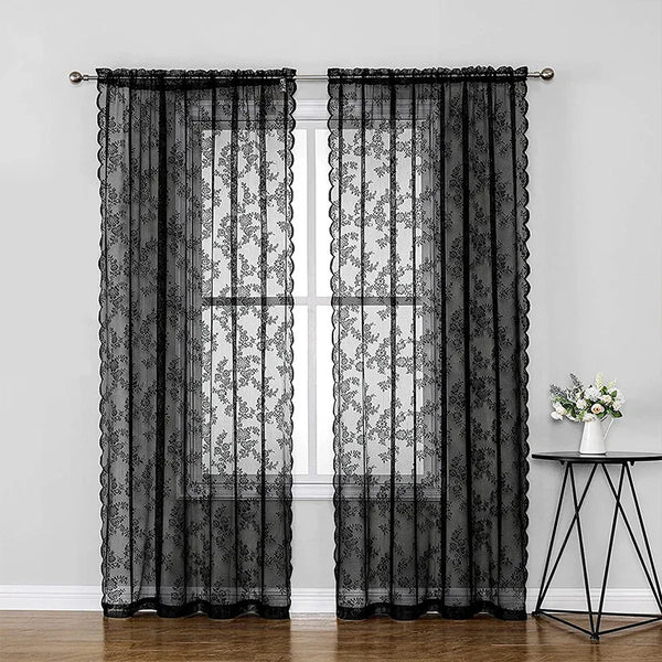 Black vintage floral lace curtains hanging in a window frame.