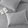 A set of gray embroidered cotton quilted pillow covers with a small white tag.