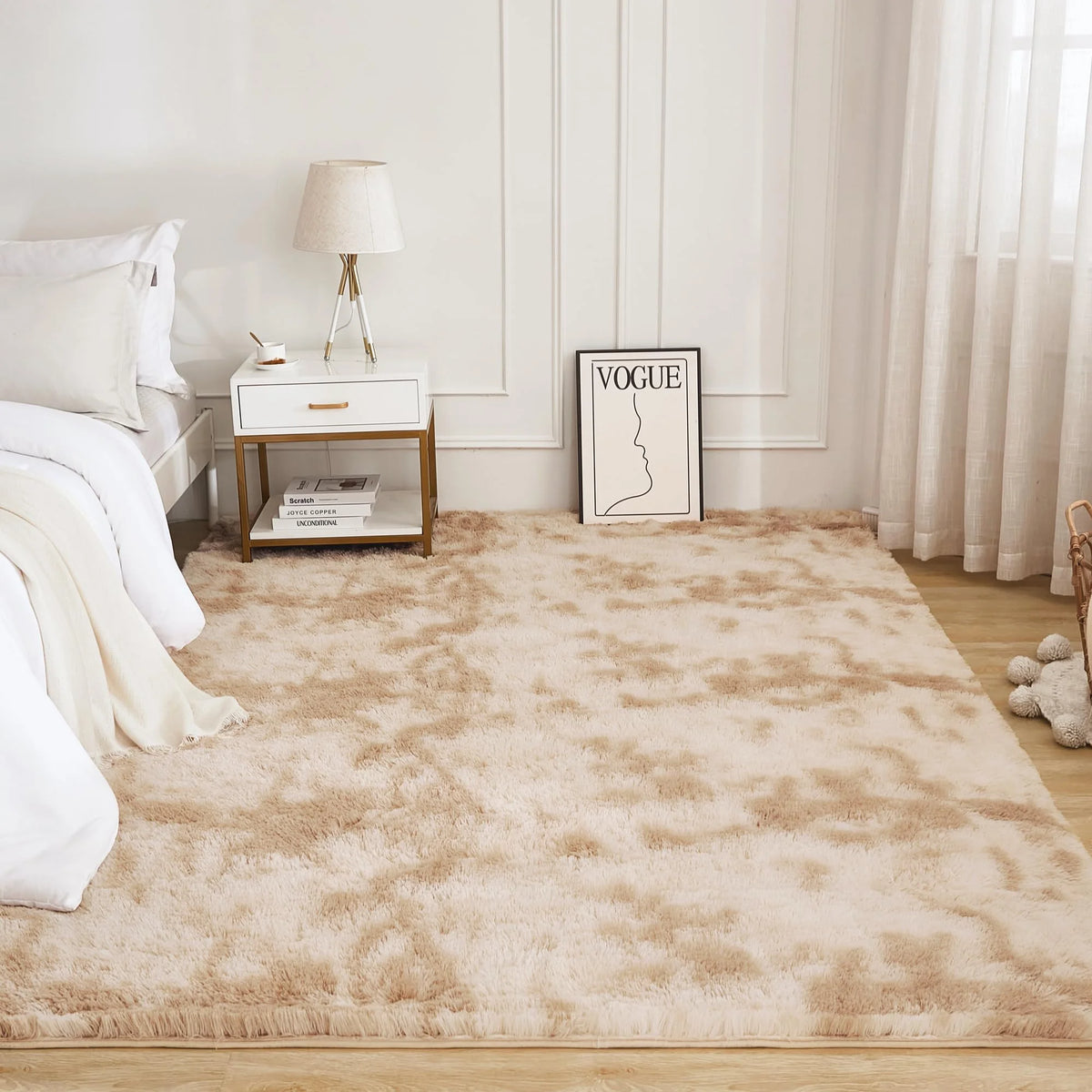 A fluffy cream tie-dye shaggy rug placed on a light wood floor in a bright room.