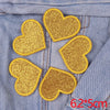Five gold glitter iron-on embroidered love heart star patches on a denim fabric