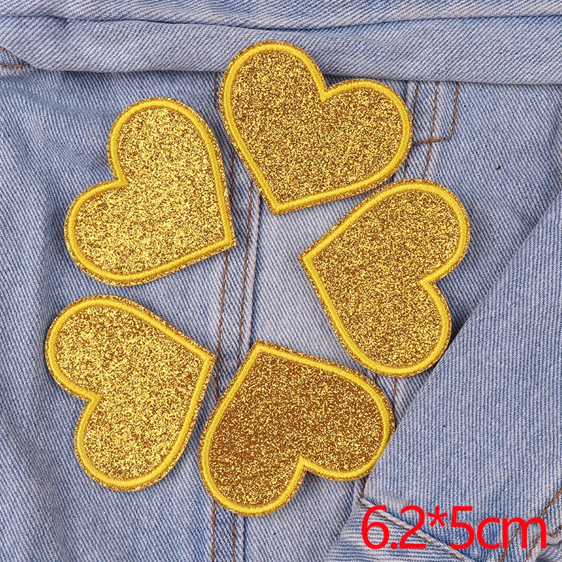 Five gold glitter iron-on embroidered love heart star patches on a denim fabric