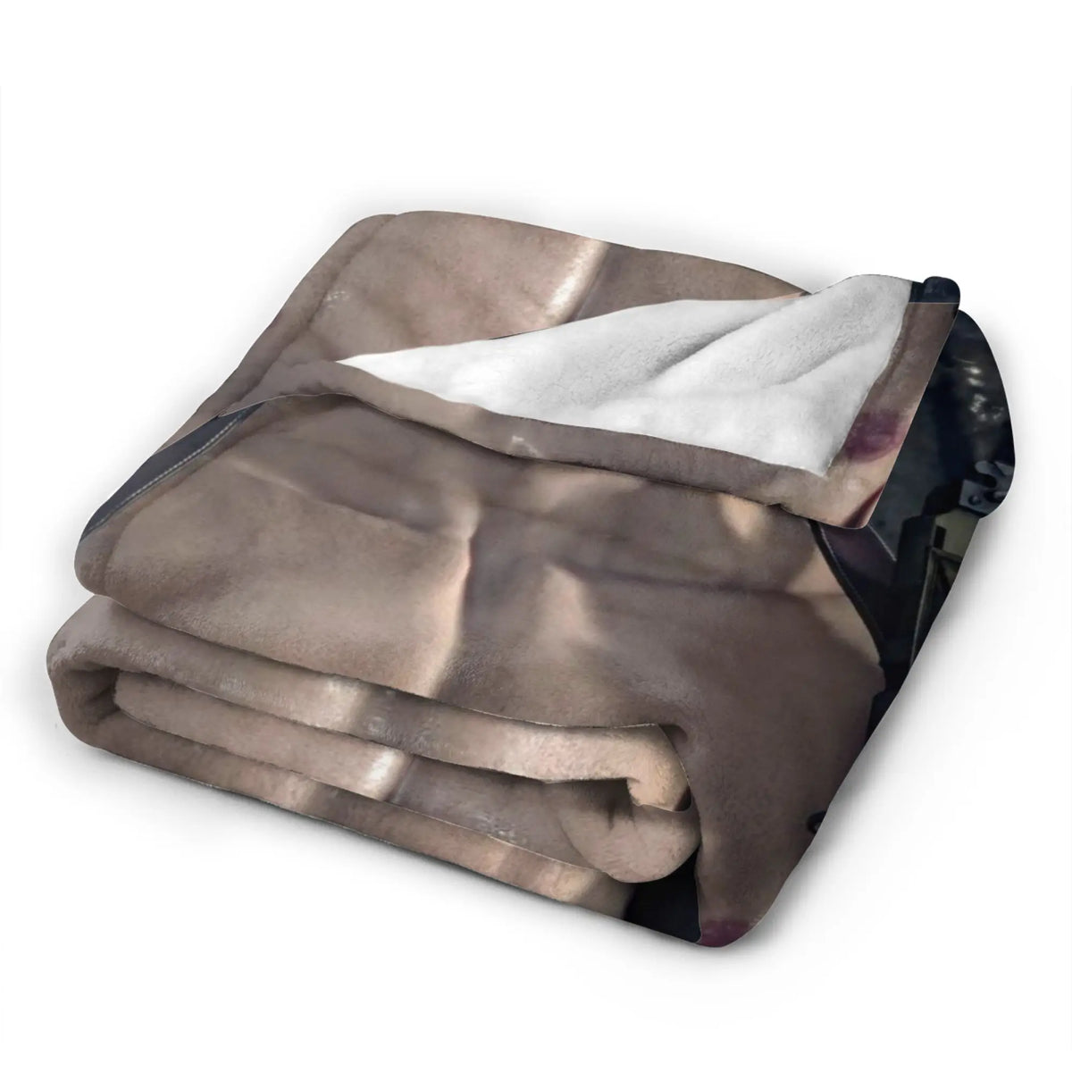 A folded beige graphic throw blanket with a white lining is shown on a dark surface.