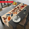 A 2D flat printing table runner featuring a floral branch design with autumn leaves and red flowers on a dark wooden table.