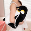 A black and white huggable giant penguin plush toy being held by a person.
