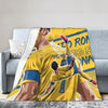 A yellow and blue graphic print on a throw blanket featuring a soccer player celebrating.