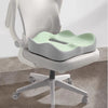 A light gray ergonomic seat cushion with a mint green insert is shown on a white office chair.